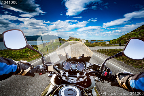 Image of Biker rides a road with Atlantic Ocean Road in Norway. First-per