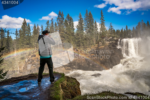 Image of Nature photographer tourist with camera shoots while standing Ri