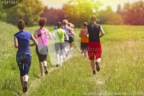 Image of Group of young athlete running marathon outdoors in sunset