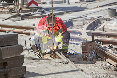 Image of Worker with protective mask welding tram tracks in the city