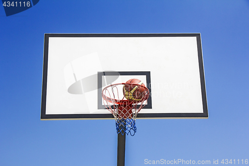 Image of Basketball ball hit the basket in the blue sky background