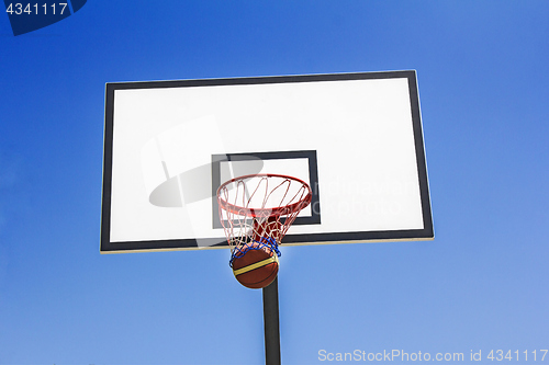 Image of Basketball ball hit the basket in the blue sky background