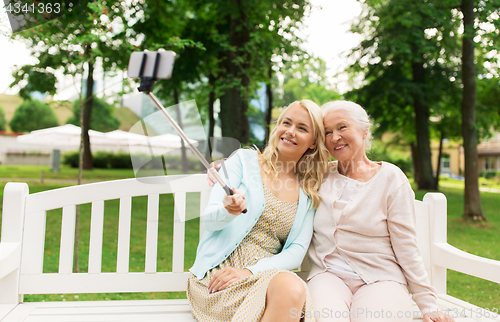 Image of daughter and senior mother taking selfie at park