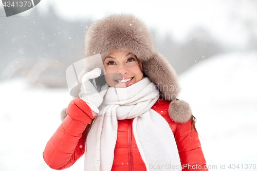 Image of happy woman in winter hat calling on smartphone