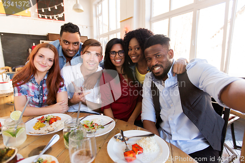 Image of happy friends taking selfie at restaurant or bar