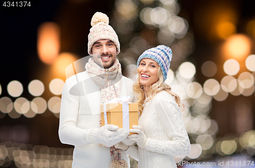 Image of happy couple with christmas gift over night lights