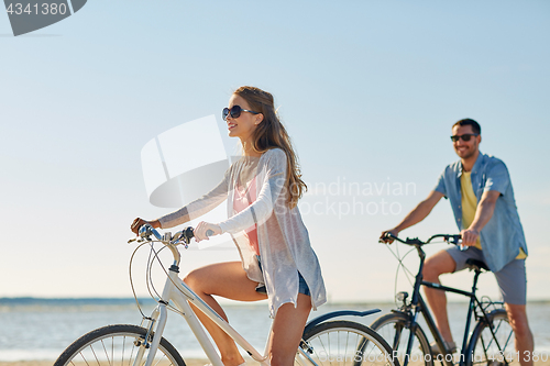 Image of happy young couple riding bicycles at seaside