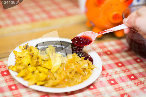 Image of hand pouring sausages with cranberry sauce