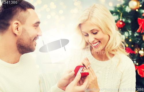 Image of man giving woman engagement ring for christmas