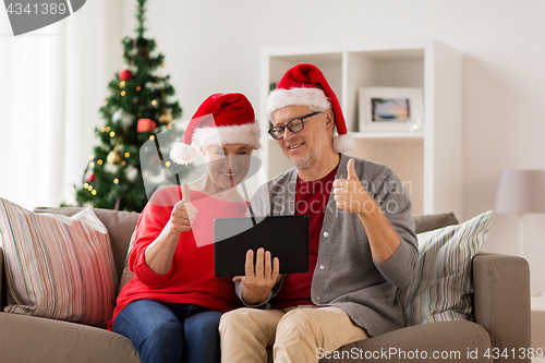 Image of happy senior couple with tablet pc at christmas