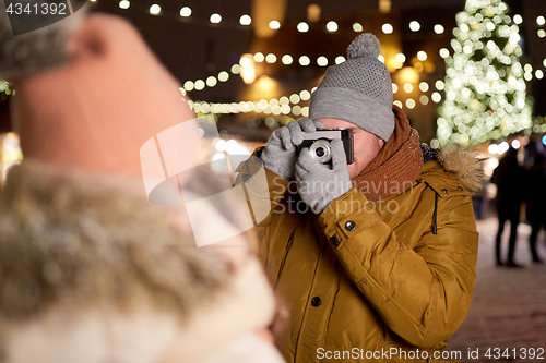 Image of man with camera photographing woman at christmas