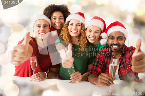 Image of happy friends showing thumbs up christmas at party