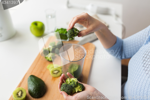 Image of woman hand adding broccoli to measuring cup