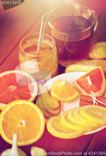 Image of ginger tea with honey, citrus and garlic on wood