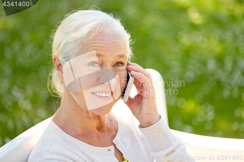 Image of happy senior woman calling on smartphone in summer