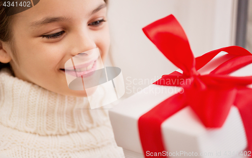 Image of happy beautiful girl with christmas gift at home
