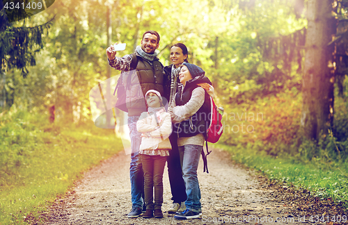 Image of family taking selfie with smartphone in woods