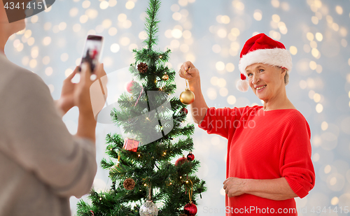 Image of happy senior woman decorating christmas tree