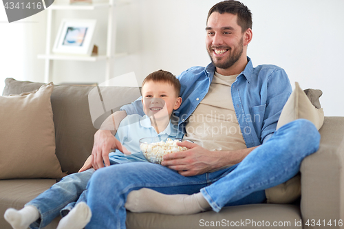 Image of father and son with popcorn watching tv at home