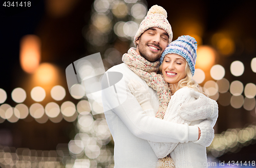 Image of happy couple hugging over christmas lights