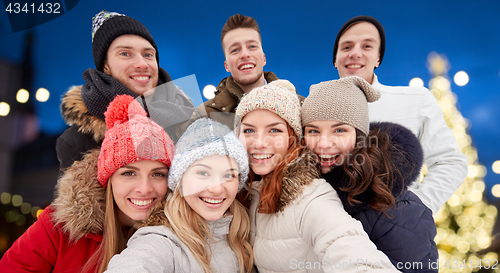 Image of happy friends taking selfie outdoors at christmas