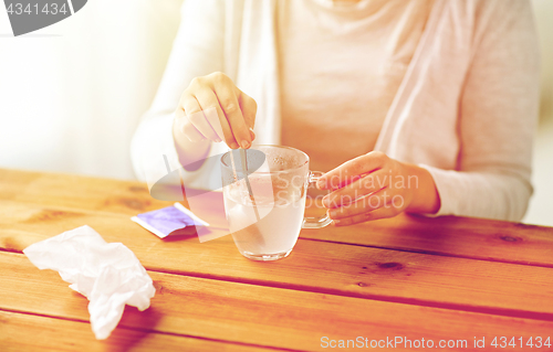 Image of woman stirring medication in cup with spoon