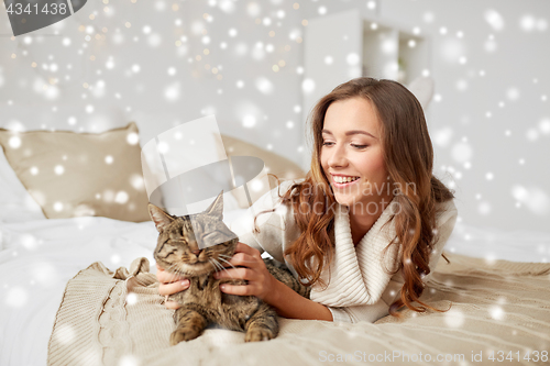 Image of happy young woman with cat lying in bed at home