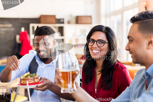 Image of happy friends eating at restaurant