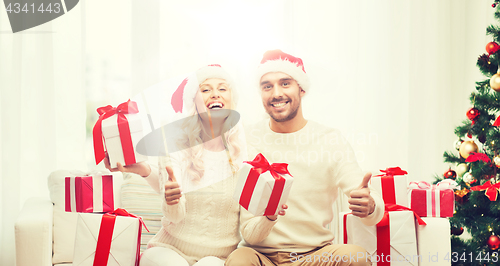 Image of happy couple with christmas gifts and thumbs up