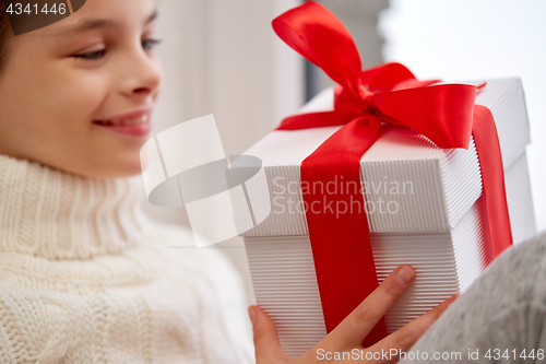 Image of girl with christmas gift sitting on sill at home