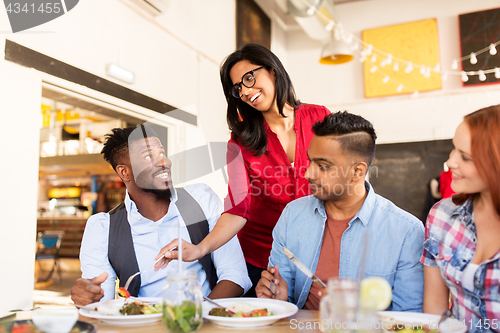 Image of happy friends eating at restaurant