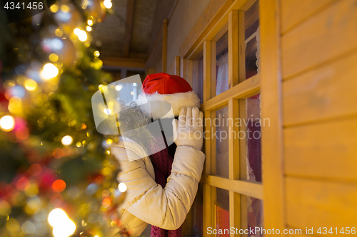 Image of woman looking to house window at christmas market