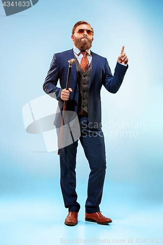 Image of The barded man in a suit holding cane.