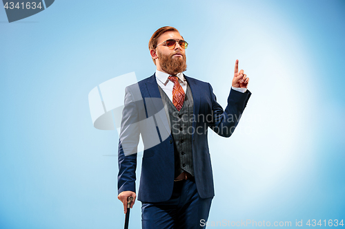 Image of The barded man in a suit holding cane.