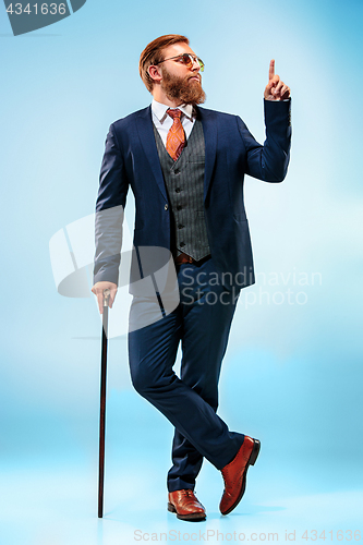 Image of The barded man in a suit holding cane.