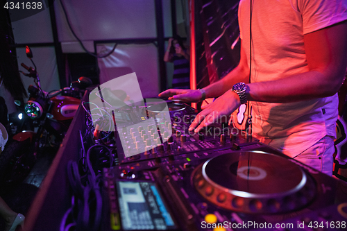 Image of DJ playing music at mixer on colorful blurred background