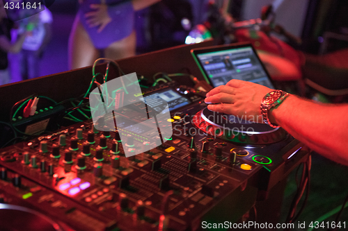 Image of DJ playing music at mixer on colorful blurred background