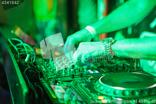 Image of DJ playing music at mixer on colorful blurred background