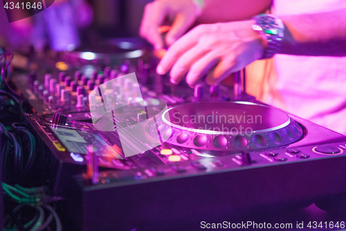 Image of DJ playing music at mixer on colorful blurred background