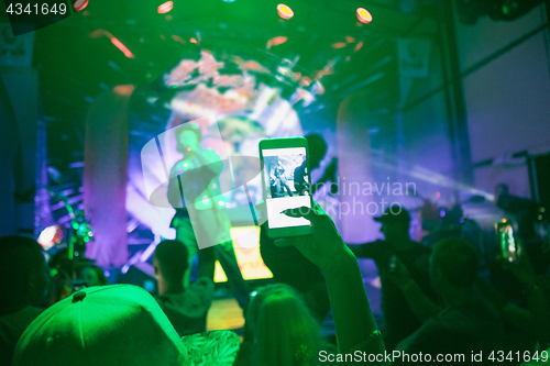 Image of The silhouettes of concert crowd in front of bright stage lights