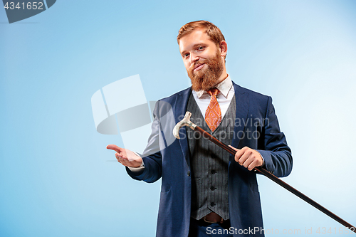 Image of The barded man in a suit holding cane.