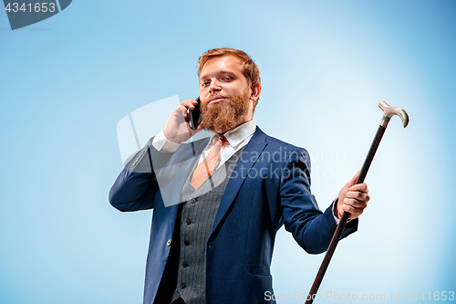 Image of The barded man in a suit holding cane.