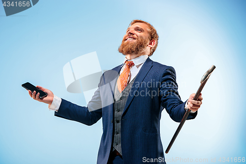 Image of The barded man in a suit holding cane.