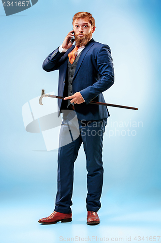 Image of The barded man in a suit holding cane.