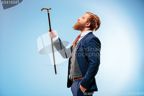 Image of The barded man in a suit holding cane.