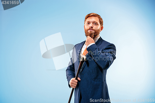 Image of The barded man in a suit holding cane.