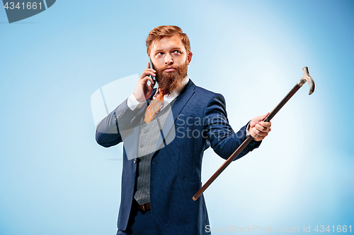 Image of The barded man in a suit holding cane.