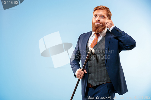 Image of The barded man in a suit holding cane.