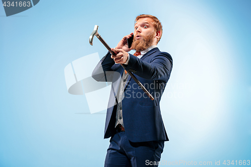 Image of The barded man in a suit holding cane.