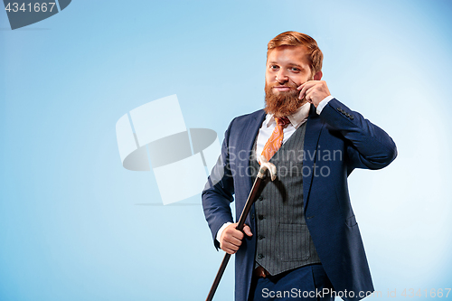 Image of The barded man in a suit holding cane.